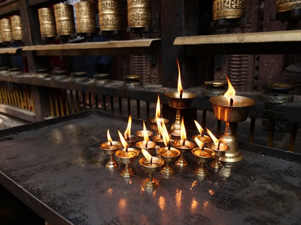 Oil lamps in front of prayer wheels in the Golden Temple Hiranya Varna Mahavihar