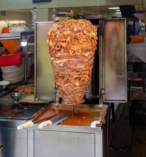 Meat grilling on vertical kebab spit in fast food street restaurant