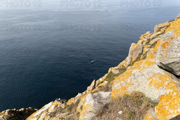 Fishing trawler boat far below steep cliffs Isla del Faro