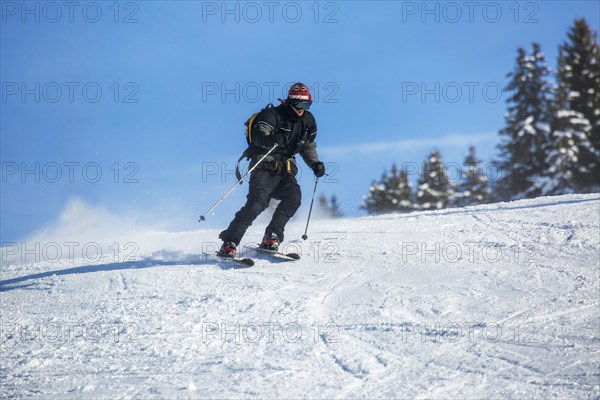 Skier skiing down ski slope in winter sports resort in the Alps