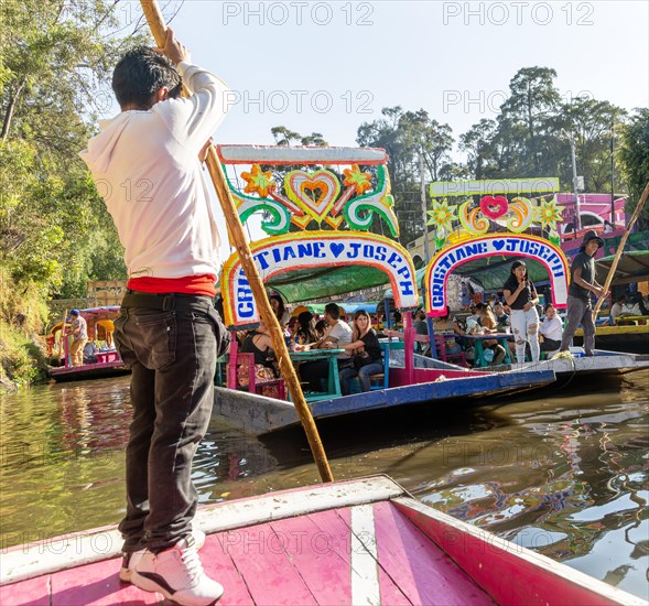 Popular tourist attraction people boating on colourful barges on canal at Xochimiloco