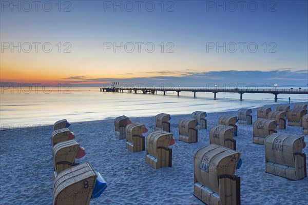 Roofed wicker beach chairs and wooden pier