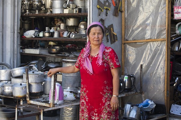 Kyrgyz woman with headscarf selling kitchen utensils