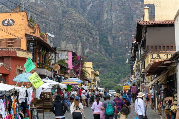 People walking along busy shopping street with mountain in distance