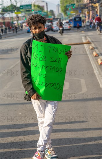 Protestor holding placard blocks traffic on busy city centre road