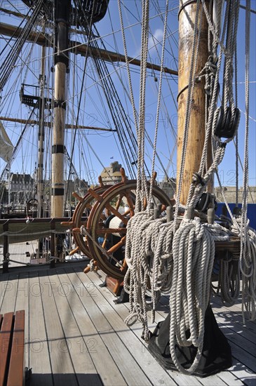 Steering wheel and ropes coiled around belaying pins aboard the Grand Turk