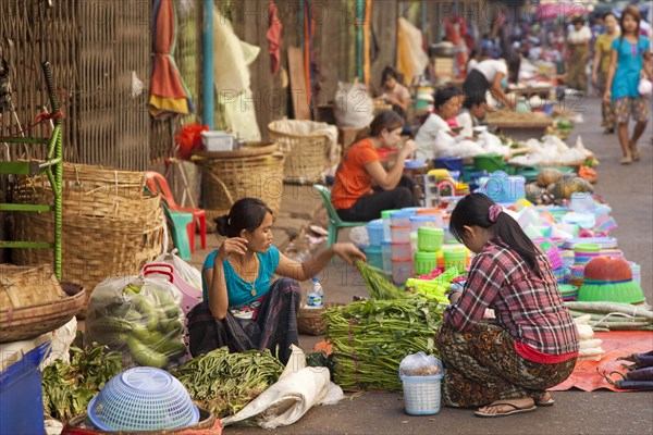 Burmese female street vendors selling food and goods on the ground at market in Yangon