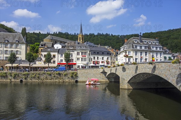 Paddle boat with tourists passing under the bridge Pont de Liege in the city Bouillon in summer