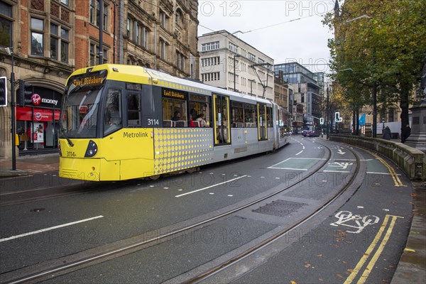 A yellow Metrolink tram passes through the city centre. Manchester