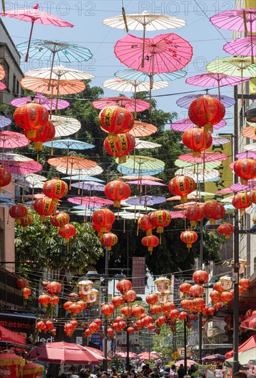 Red paper Chinese lanterns and umbrellas hanging above the street in Chinatown