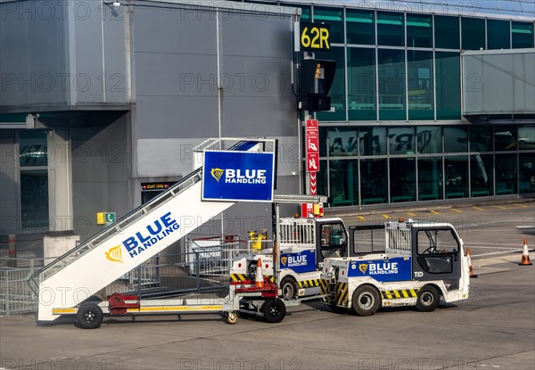 View through plane window Blue Handling aviation vehicles at London Stansted Airport