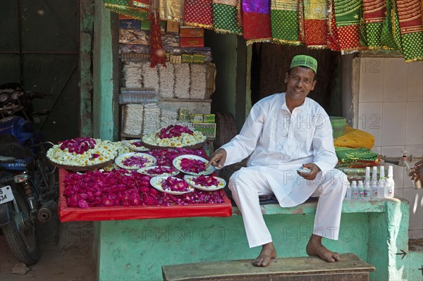 Vendor in front of shop selling scarfs and flowers as gifts for offerings near the Nizam-Ud-Din shrine in Delhi