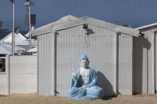 Buddha figure in front of a white beach hut