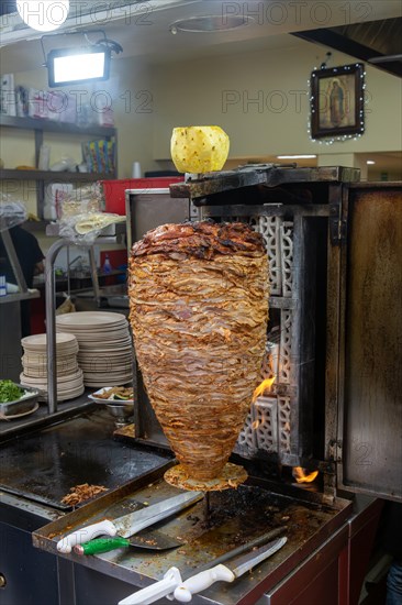 Meat grilling on vertical kebab spit in fast food street restaurant