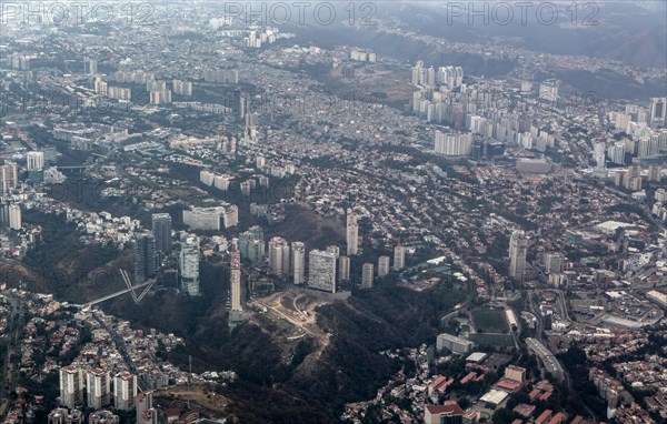 Oblique angle aerial view through plane window of suburbs approaching Mexico City