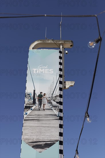 Advertising pillar Good Times with image of a holidaymaker couple