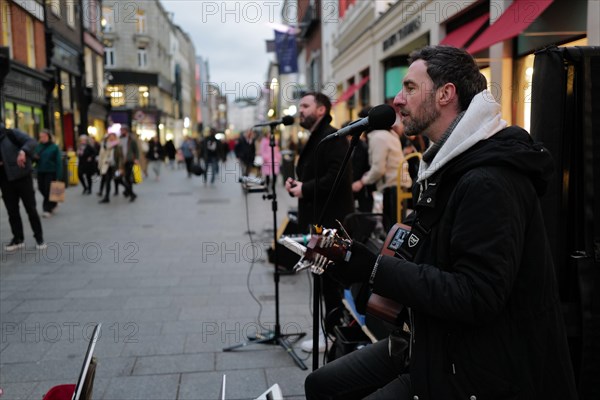 Andrew Glover of Irish pop group Keywest playing in Grafton Street with lead singer Andrew Kavanagh is in the back ground. Dublin