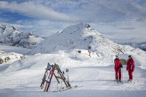 Two Swiss female ski instructors waiting on top of ski run in winter sports resort in the Alps