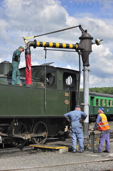 Engine driver filling boiler of steam train from water crane at the depot of the Chemin de Fer a Vapeur des Trois Vallees at Mariembourg