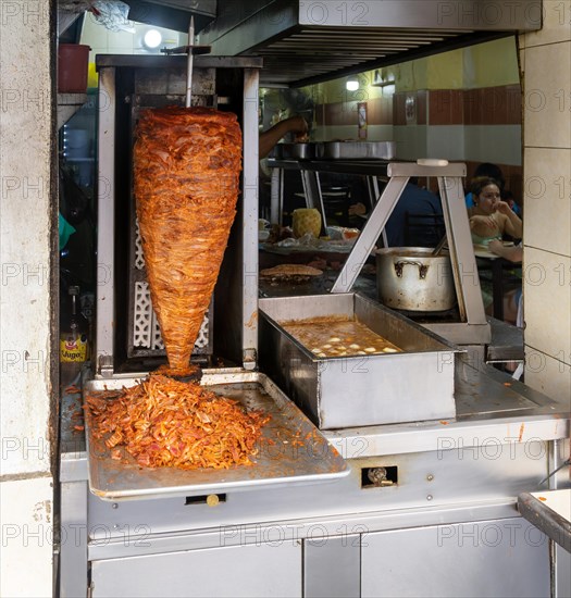 Meat grilling on vertical kebab spit in fast food street restaurant