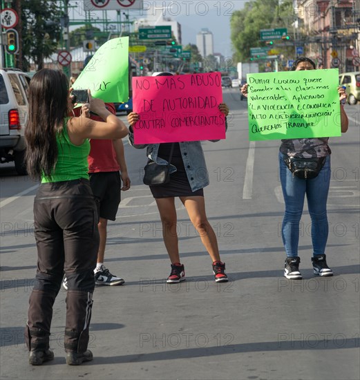 Female protestors holding placards against abuse and domestic violence block traffic on busy city centre road