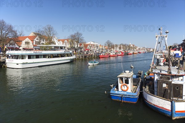 Sightseeing boat and traditional fishing boats in the canal der Alte Strom at Warnemuende in the city Rostock at dusk