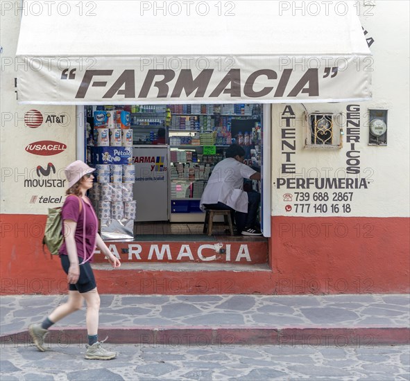 Woman walking past small pharmacy shop