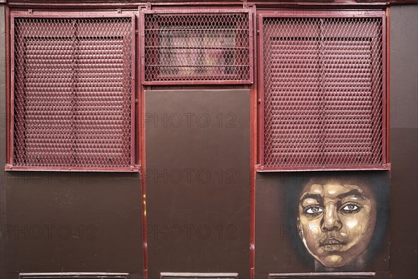 Painted portrait of a child on a barred window wall
