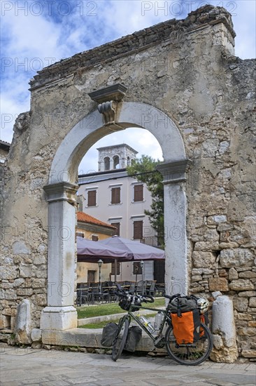 Touring bicycle in front of remains of ancient Roman city gate in the town Pore?