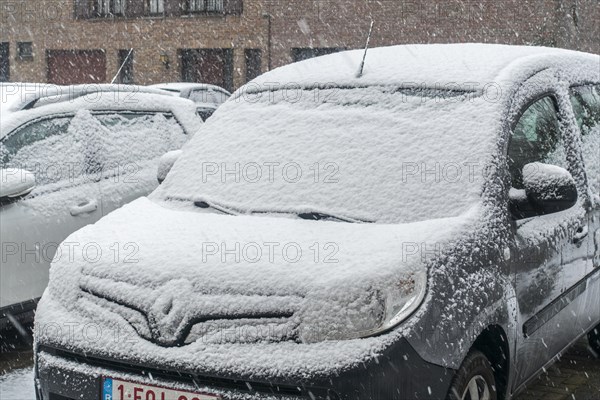 Parked cars covered in snow during unexpected late snow shower in March 2023