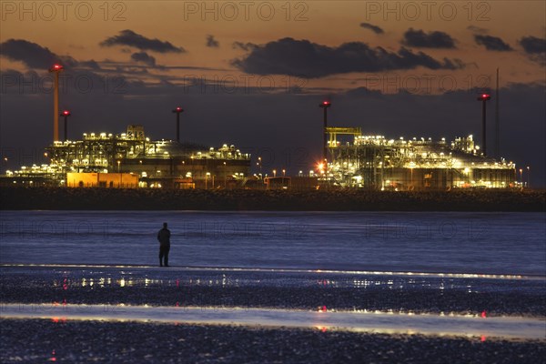 Man looking at the Zeebrugge North Sea port at sunset