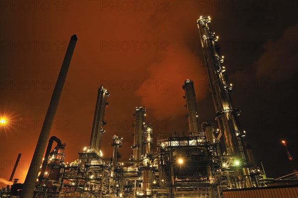 Refinery chimneys of petrochemical industry illuminated at night