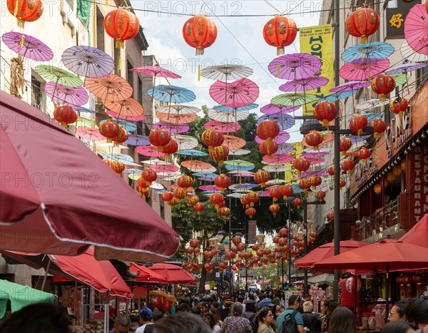 Red paper Chinese lanterns and umbrellas hanging above the street in Chinatown