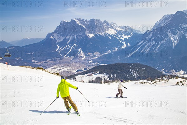 Skiers and snowboarders on the panoramic run with a view of the Zugspitze