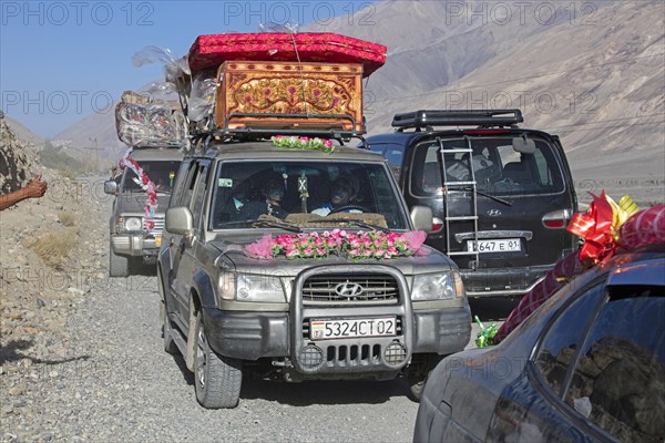 Decorated vehicles loaded with presents on their way to a traditional wedding on the Pamir Highway