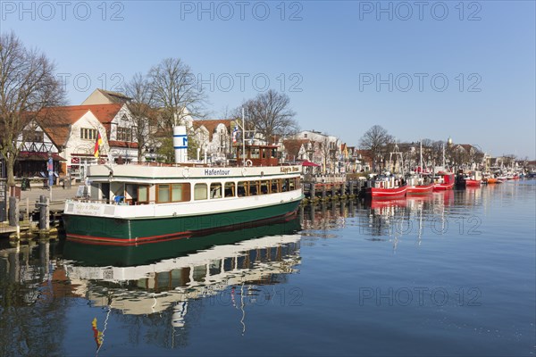 Sightseeing boat and traditional fishing boats in the canal der Alte Strom at Warnemuende in the city Rostock at dusk