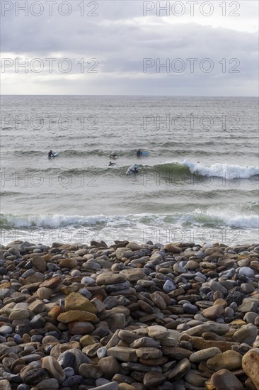 Stones on the beach as surfers ride the waves along the Wild Atlantic way. Strandhill