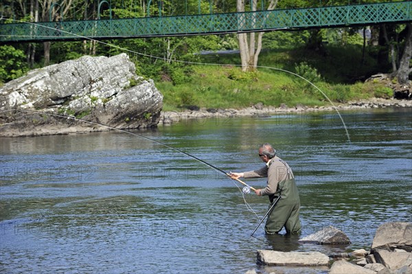 Angler fly fishing for salmon in a river in Scotland