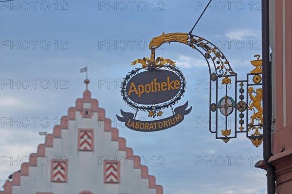 Nose shield of the court pharmacy with golden inscription Laboratorium and blurred stepped gable of the town hall