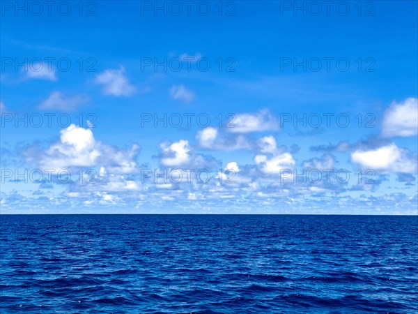 Clouds Altocumulus reflected in front of blue sky on horizon over Pacific Still ocean with no waves with in mirror smooth sea surface water surface mirror smooth sea