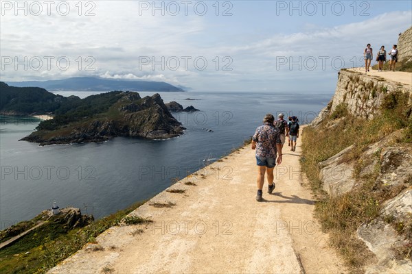 People walking on pathway to lighthouse