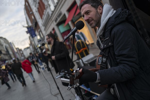 Andrew Glover of Irish pop group Keywest playing in Grafton Street with lead singer Andrew Kavanagh in the back ground. Dublin