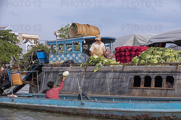 Vietnamese farmer selling vegetables from traditional wooden boat at the floating market of the city Can Tho in the Mekong Delta