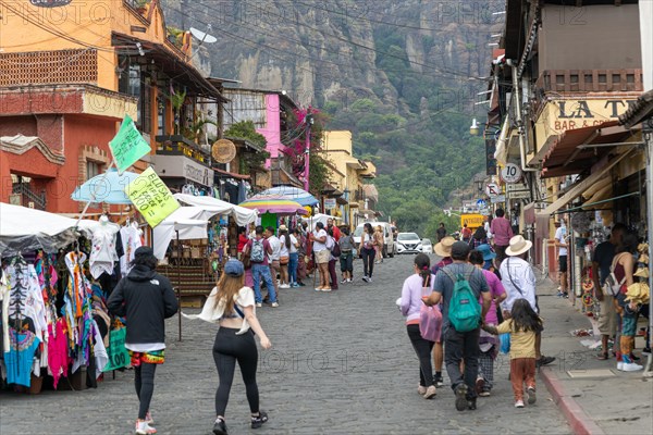 People walking along busy shopping street with mountain in distance