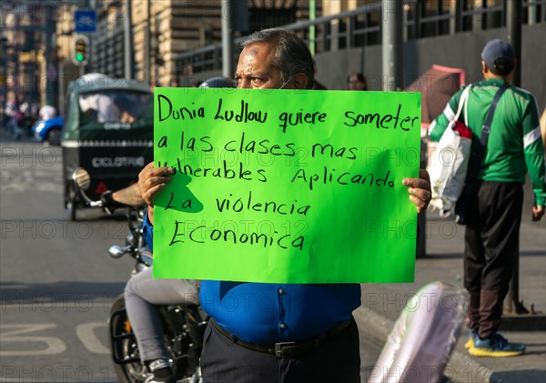 Protestor holding placard blocks traffic on busy city centre road