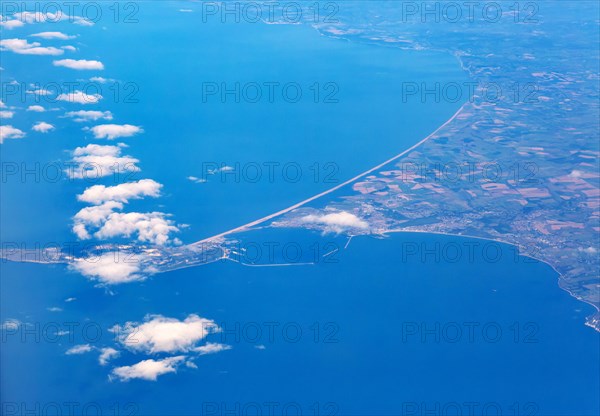 Oblique aerial view through plane window of Chisel Beach tombolo and Portland Bill island