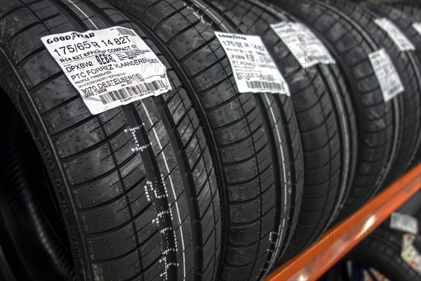 Row of new summer tires on shelf stored in tire centre