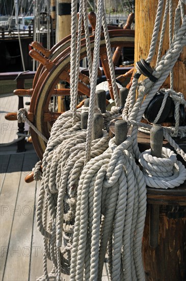 Steering wheel and ropes coiled around belaying pins aboard the Grand Turk