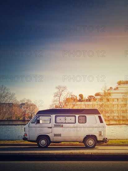 Old van parked on the edge of the street in the sunset sky background