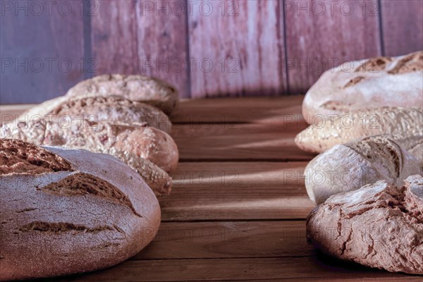 Different types of loaves and loaves of rustic artisan bread in a row on a wooden table with a copy space in the center